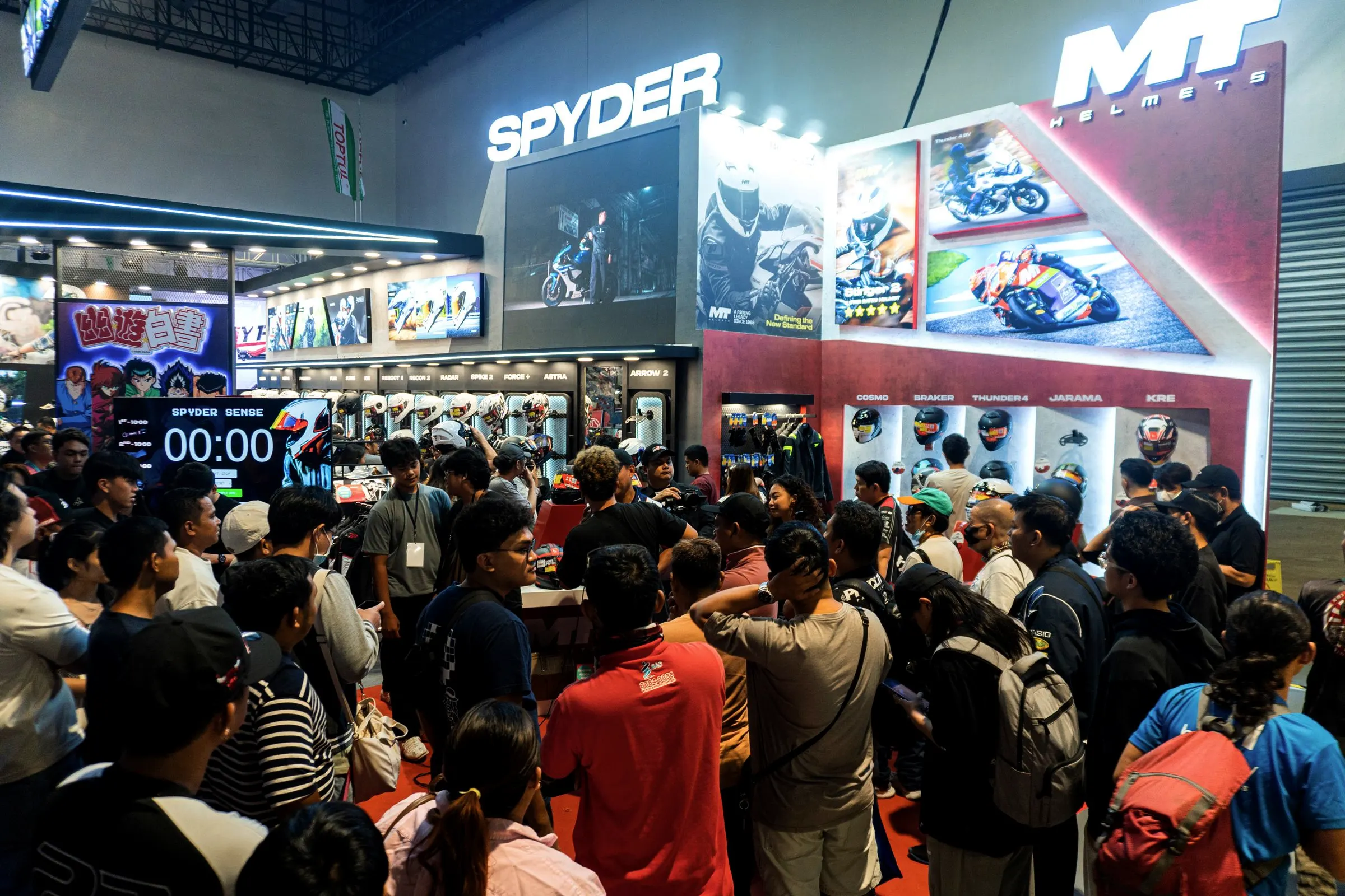A crowd packed in front of the Spyder and MT Helmets booth at a motorcycle show