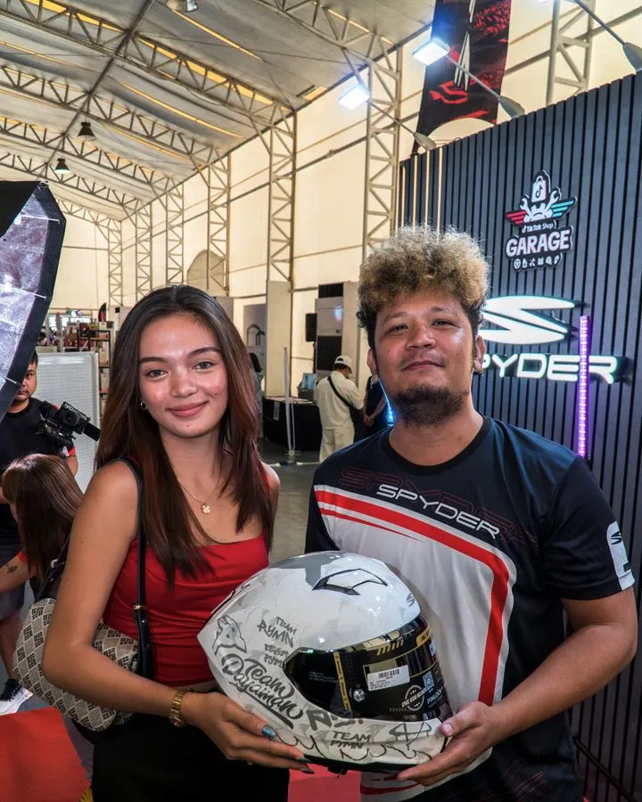 Two team members with a Spyder helmet at the Spyder Garage