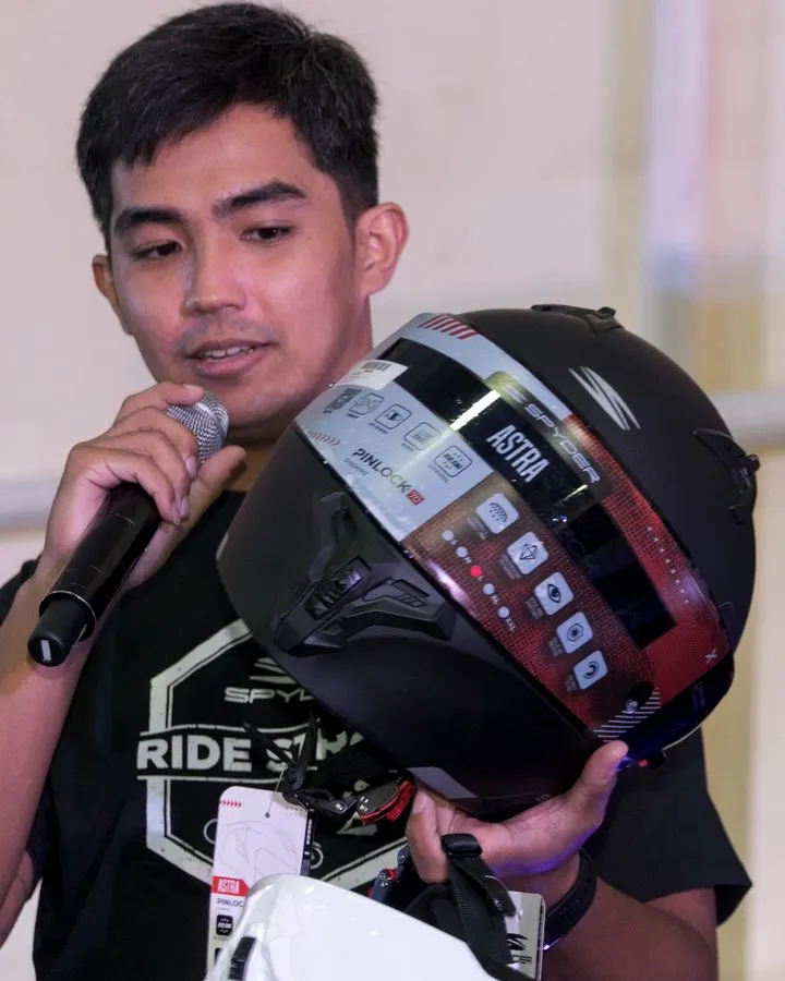 A host with a microphone and a helmet on stage