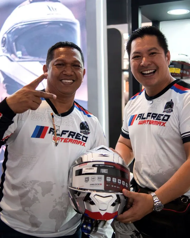 Two partners holding up a helmet at a handover
