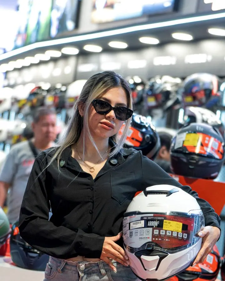 A team member in sunglasses holding a helmet at the booth