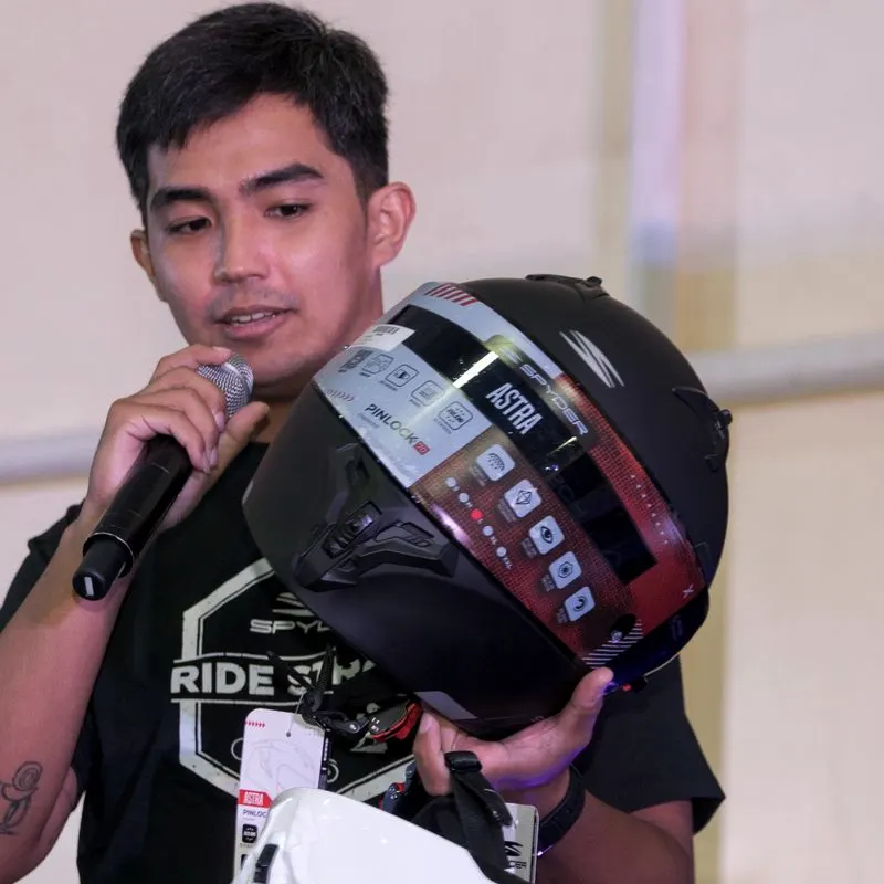 An event host on the mic, holding up a helmet